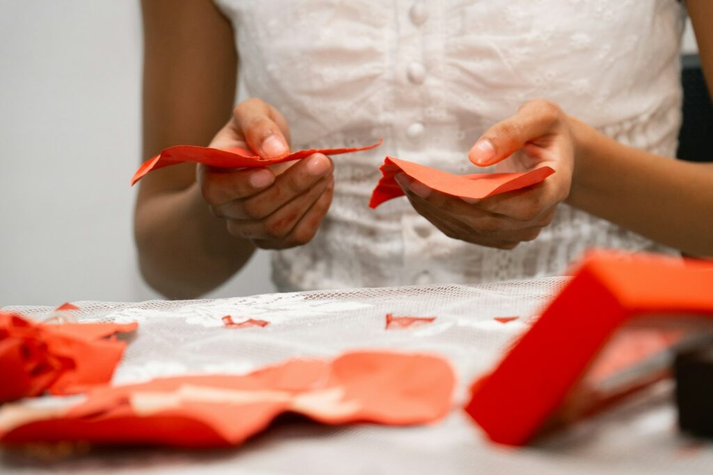 Hands folding red paper for a simple craft project at home