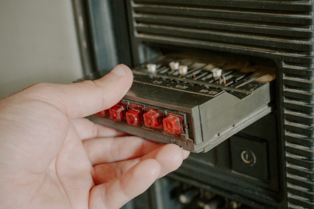 Hand inserting an old audio cassette into a player, recalling 1990s gadgets